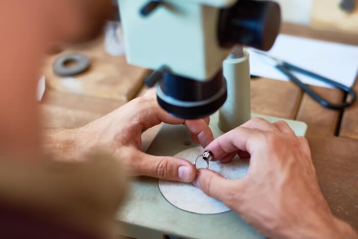 Man examining ring under microscope