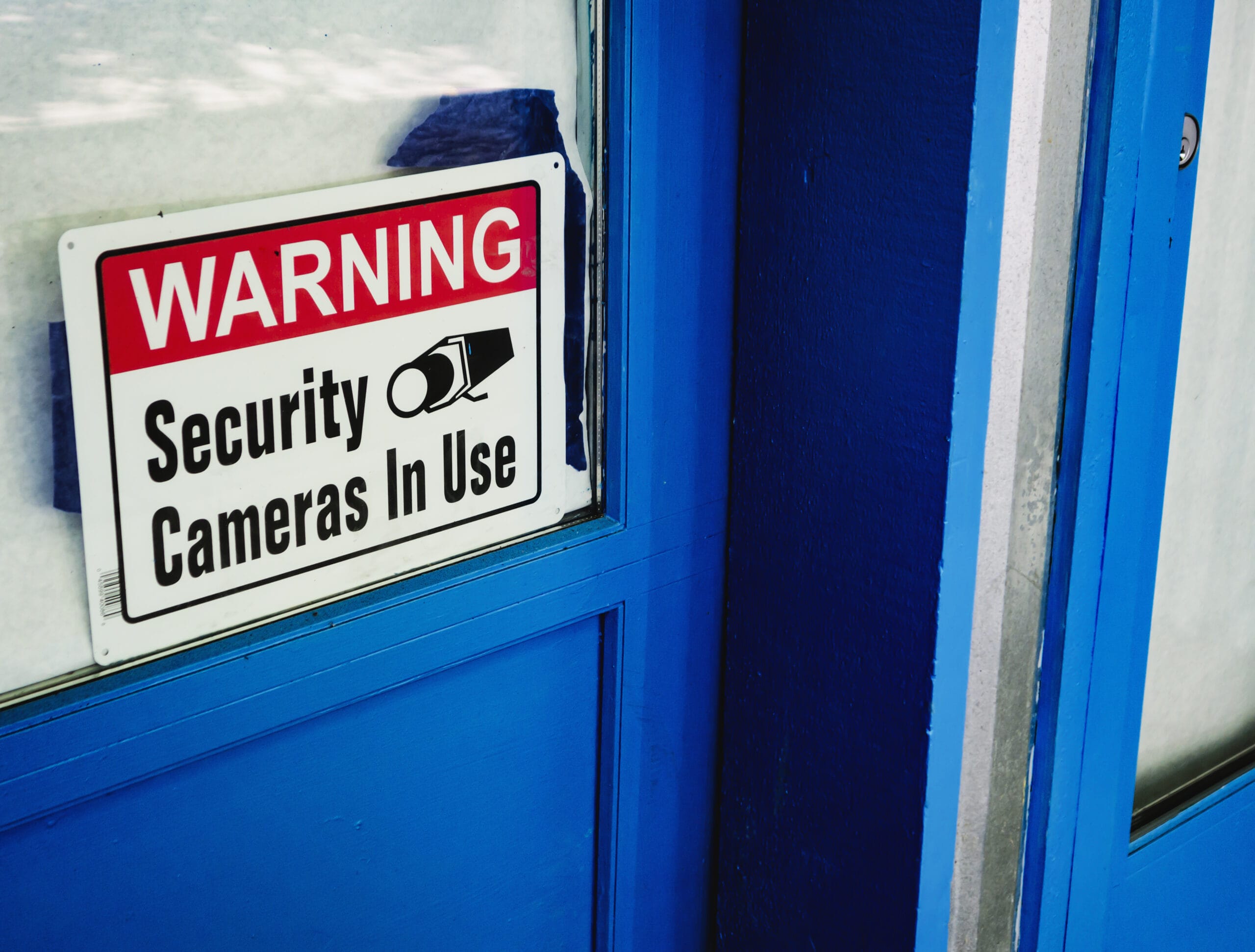 Security camera sign on blue door of los angeles pawn shop